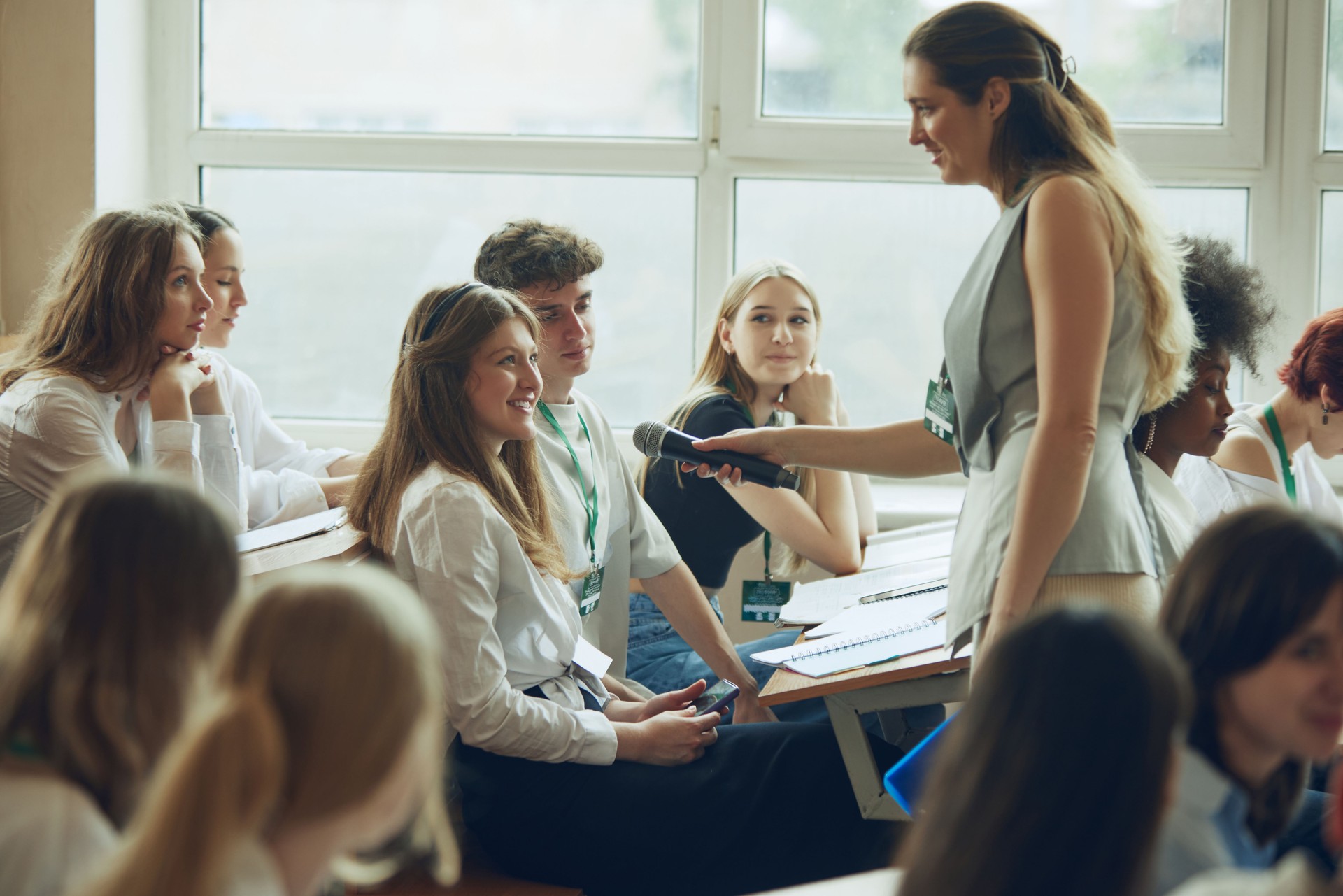 Young woman, speaker giving a talk to young girl. Lecturer leading meeting with young people, students in university.